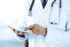 A GP holding a medical record with a stethoscope around their neck.