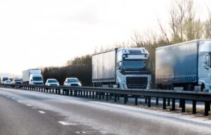 A lorry convoy drives along the motorway among other cars.