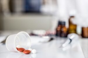 A plastic cup of pills spills onto a table