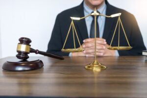 A solicitor sits at a desk behind a golden scale and gavel