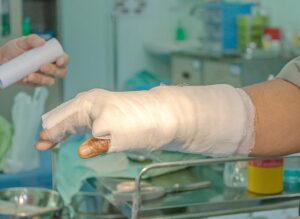 A hand wrapped in bandages with a hospital setting in the background. 