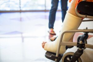 A patient in a wheelchair wearing a cast on their leg.