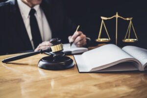 a solicitor working on his client's email data breach compensation claim at a desk with a gavel hammer and set of justice scales