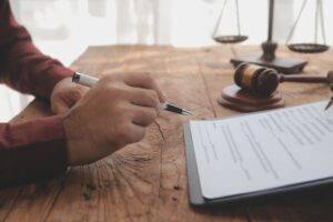 A client signing a scaffolding accident claims agreement at a lawyer's desk with a gavel on. 