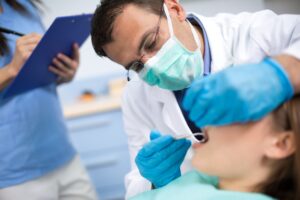 A dentist placing a small tool in a patient's open mouth.