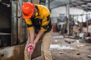 A construction worker holding his hand after suffering a serious crush injury