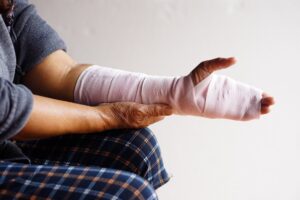 A person sits with a bandaged hand.