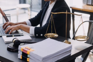 Lawyers works on breast cancer misdiagnosis claim on desk with scales, gavel, and stack of papers.