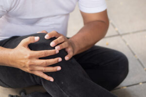 A man holds his knee after accidentally falling, which is a common cause of slip and trip claims.