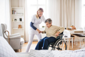 A care home resident being assisted out of a wheelchair by a member of staff