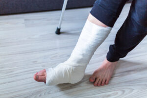 A man trying to stand up on crutches with his ankle and lower leg in a plaster cast